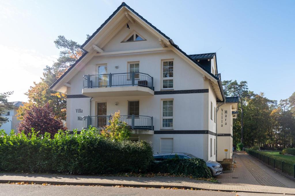 a white house with a balcony on a street at Villa Mara Wohnung 3 in Baabe