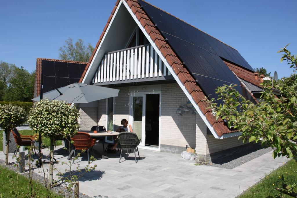 a woman sitting at a table in front of a house at Haus Reiher Am Lauwersmeer in Anjum