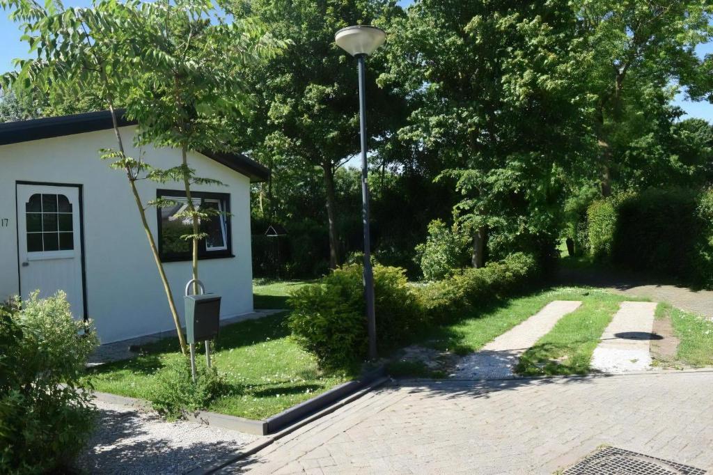 een huis met een straatlicht naast een oprit bij Kleines Haus Mit Garten, Direkt Hinter Dem Deich in Baarland