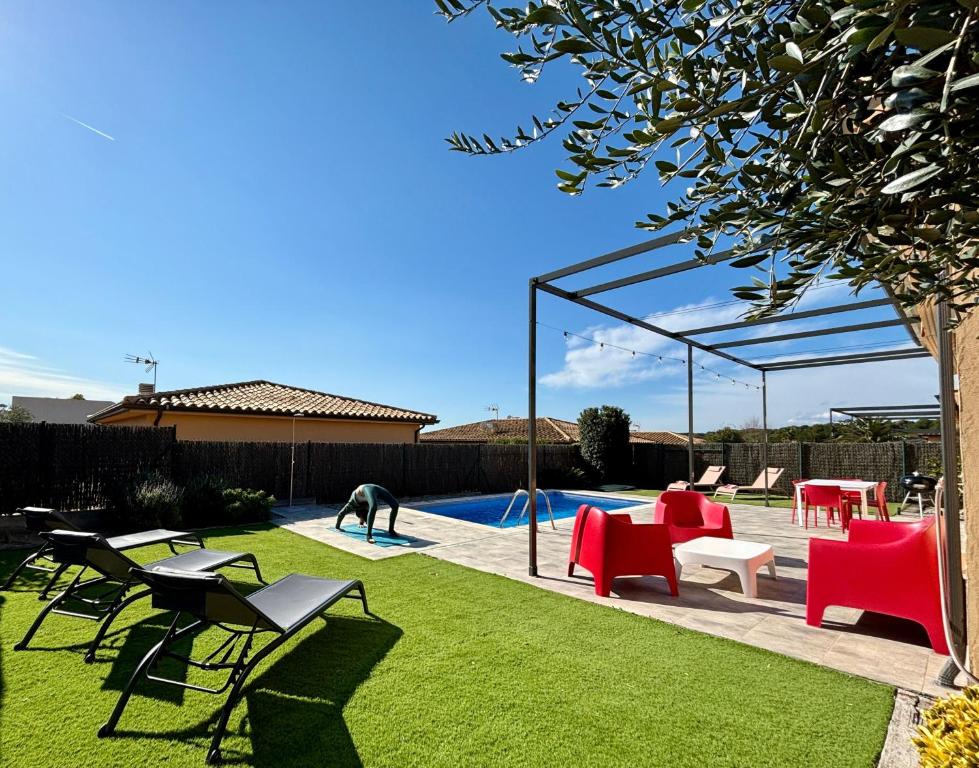 ein Garten mit Pool, roten Stühlen und einem Tisch in der Unterkunft Modernes Einfamilienhaus mit privatem Pool Villa Medes Mar in l'Estartit - b52677 in Torroella de Montgrí
