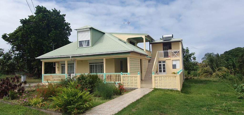 une petite maison jaune avec un toit vert dans l'établissement Appartement de type T4, à Capesterre