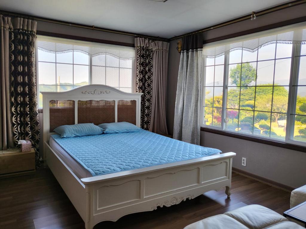Noel's Darak Pension في دانيانغ: غرفة نوم بها سرير في غرفة بها نوافذ