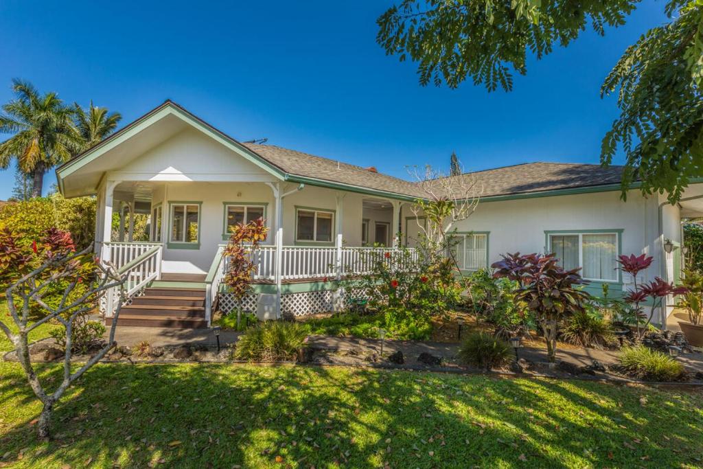 a white house with a porch and landscaping at Hale Cassia in Princeville