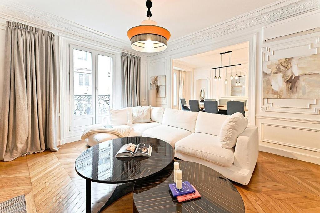 un salon avec un canapé blanc et une table en verre dans l'établissement Spacious and Bright Apartment, à Paris