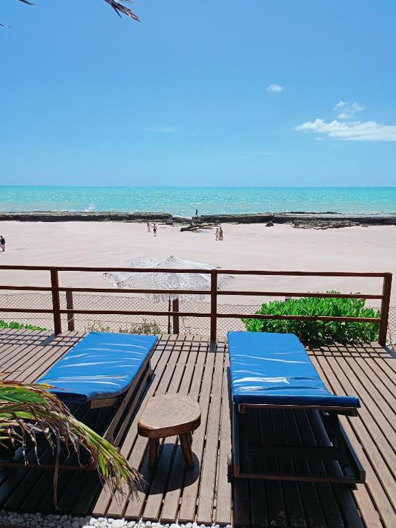 two blue benches on a wooden deck near the beach at Vila Bello Pontal in Coruripe