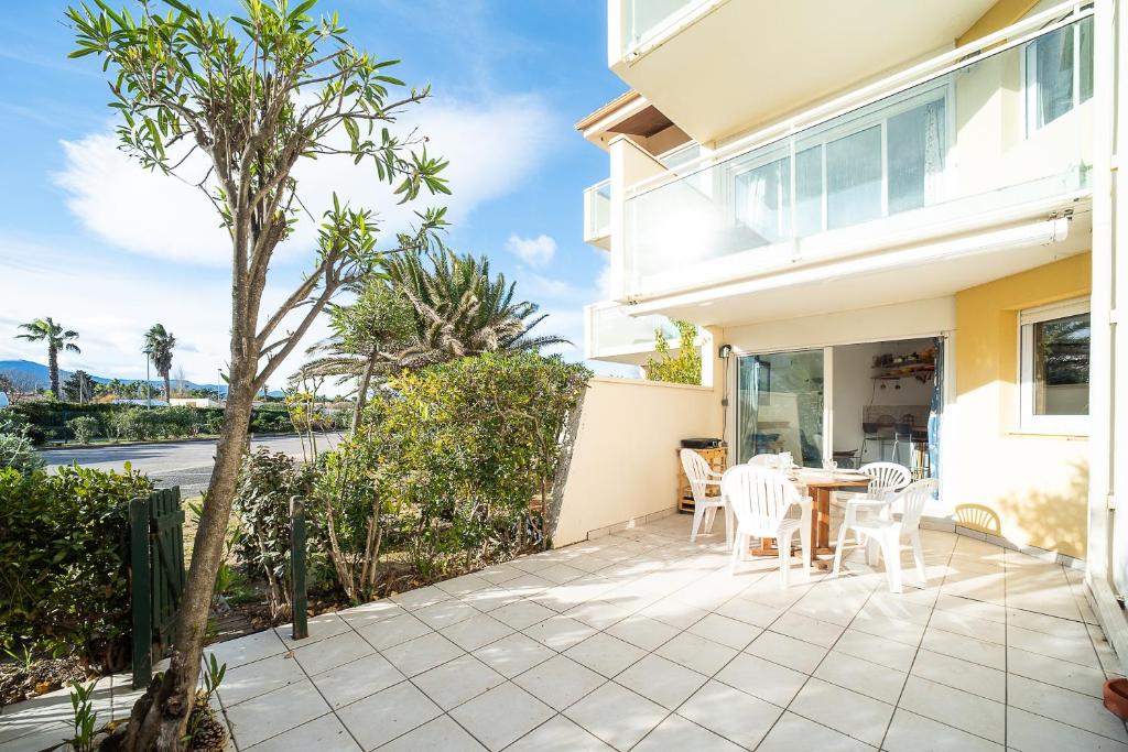 un patio avec une table et des chaises devant une maison dans l'établissement Les Goélettes - Vue mer et montagne plage à 100m, à Saint-Cyprien