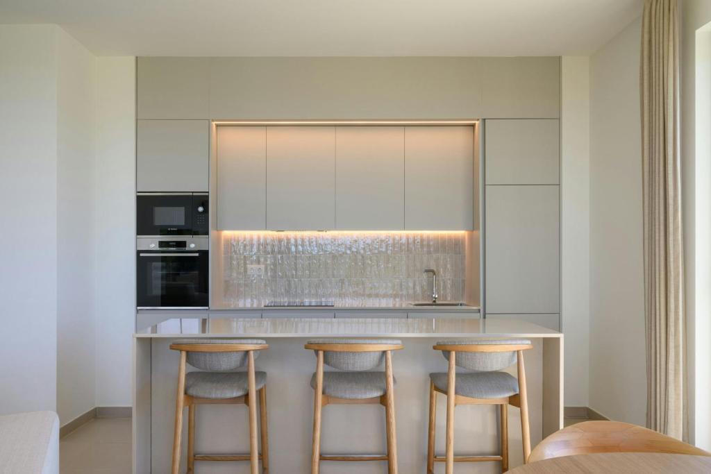 a kitchen with a counter with three bar stools at The Westin Salgados Beach Resort, Algarve in Albufeira