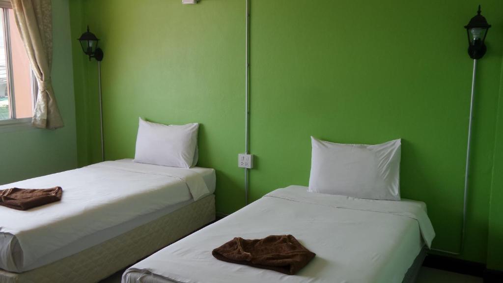 2 camas en una habitación con paredes verdes en Usabuy, en Trang
