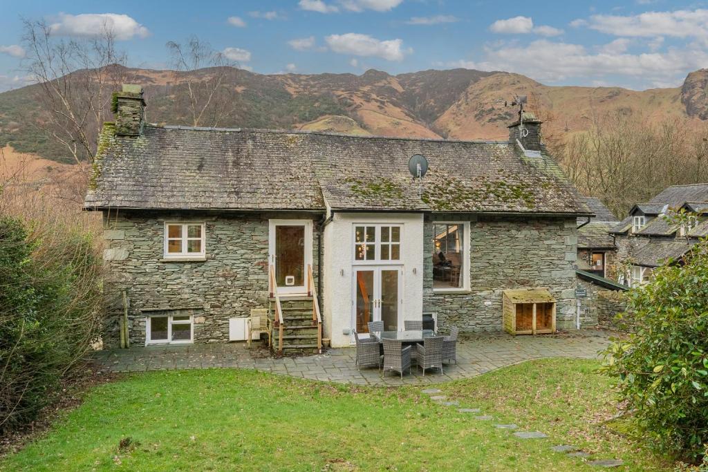 an old stone house with a porch and a patio at Cozy Lake District House on the fells in Ambleside