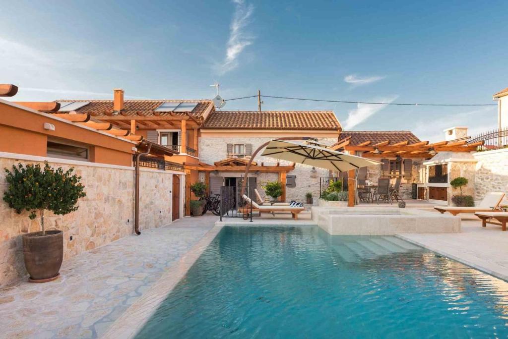 ein Haus mit einem Pool mit Sonnenschirm in der Unterkunft Luxury Villa Finessa Skradin 2 with heated pool, jacuzzi and sauna in Skradin