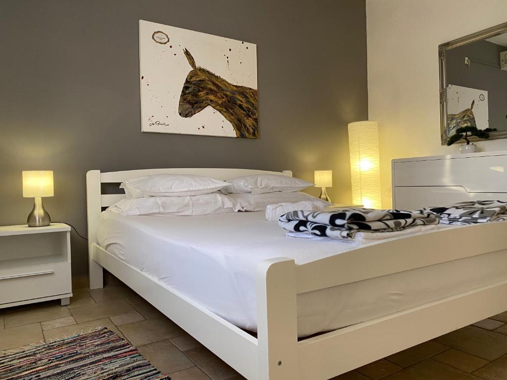 a bedroom with a white bed with a horse picture on the wall at Strandnahes Haus Lolinka Mit Schattiger Terrasse in Bibinje