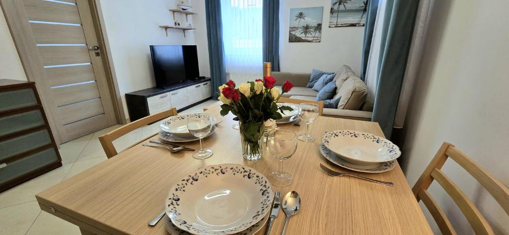 a dining room table with plates and flowers on it at Apartament PrzyLesie Jantar by TriApart in Jantar