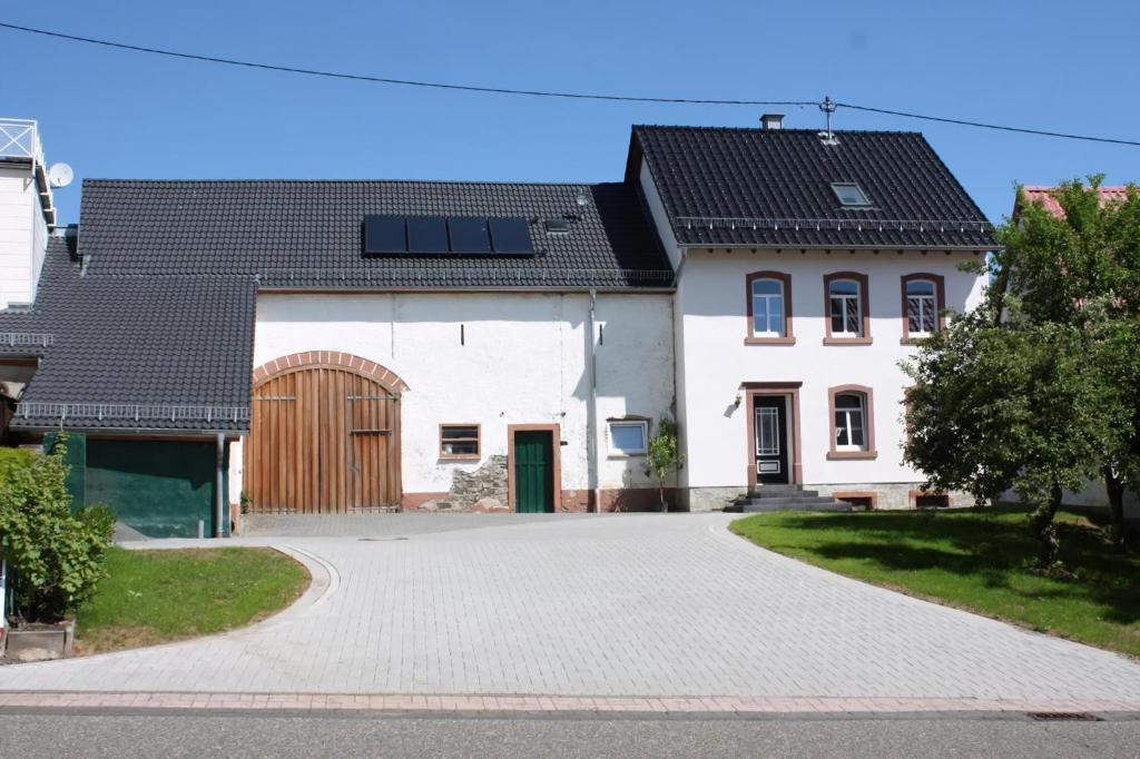 Casa blanca con paneles solares en el techo en Ferienhaus Schäwisch, en Dreis-Brück