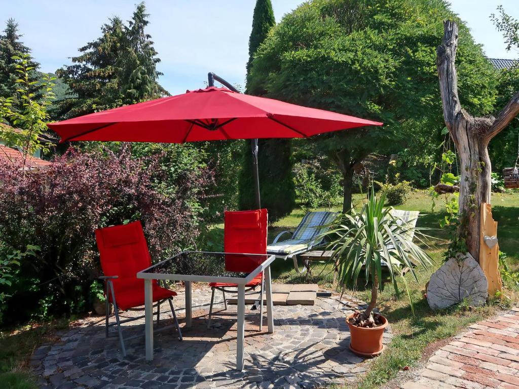 a table and two chairs under a red umbrella at Gemütliches Ferienhaus In Fischbach Rhön in Kaltennordheim