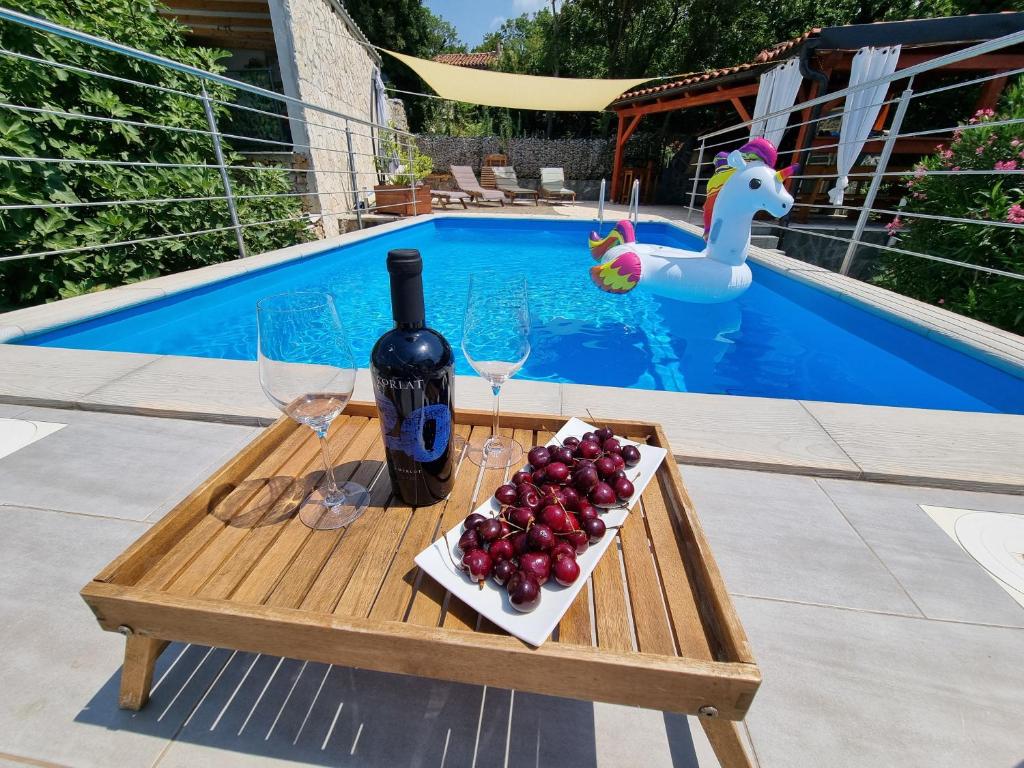 einen Tisch mit einer Flasche Wein und Gläsern neben einem Pool in der Unterkunft Ferienhaus für 8 Personen ca 300 qm in Jadranovo, Kvarner Bucht Crikvenica und Umgebung in Jadranovo