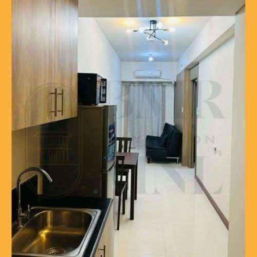 a kitchen with a sink and a living room at Staycation BMR Mnl at Coast Residences in Manila