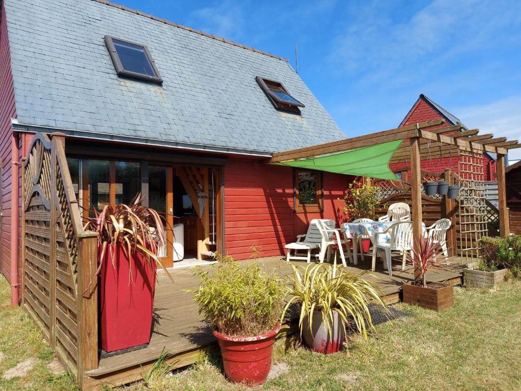 une maison rouge avec une terrasse dotée de chaises et de tables dans l'établissement Face à la mer, maison sur la dune pour 4 personnes, à Plouguerneau