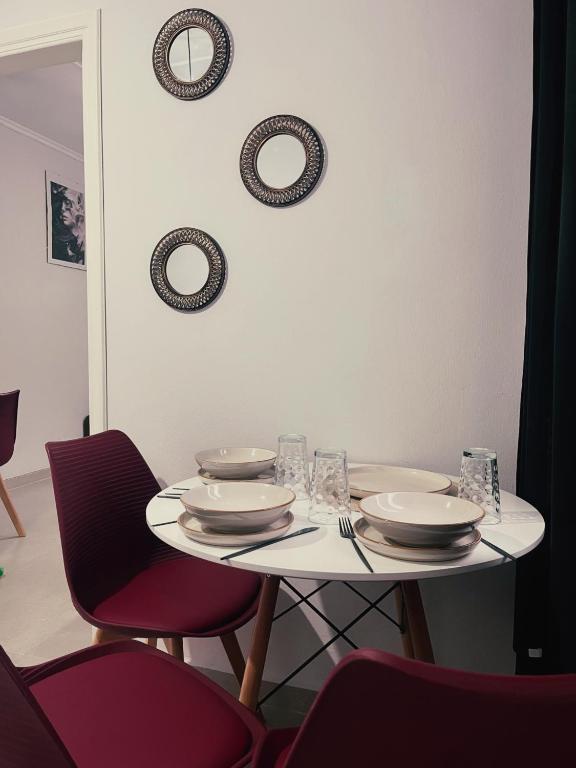 a white table with plates and bowls and chairs at Relatives Apartment in Mytilene