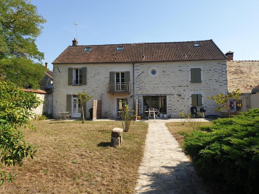 une grande maison en pierre blanche avec un chemin en face de celle-ci dans l'établissement Gîtes Auversois, à Auvers-Saint-Georges