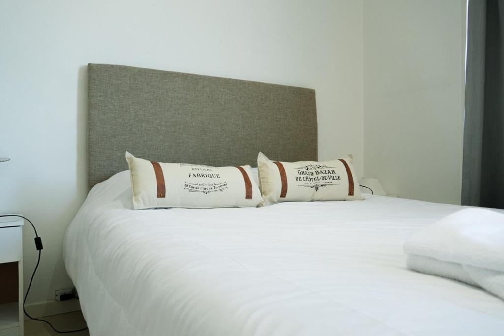 a white bed with three pillows on top of it at Ideal si venis por trabajo, con cochera in Benavídez