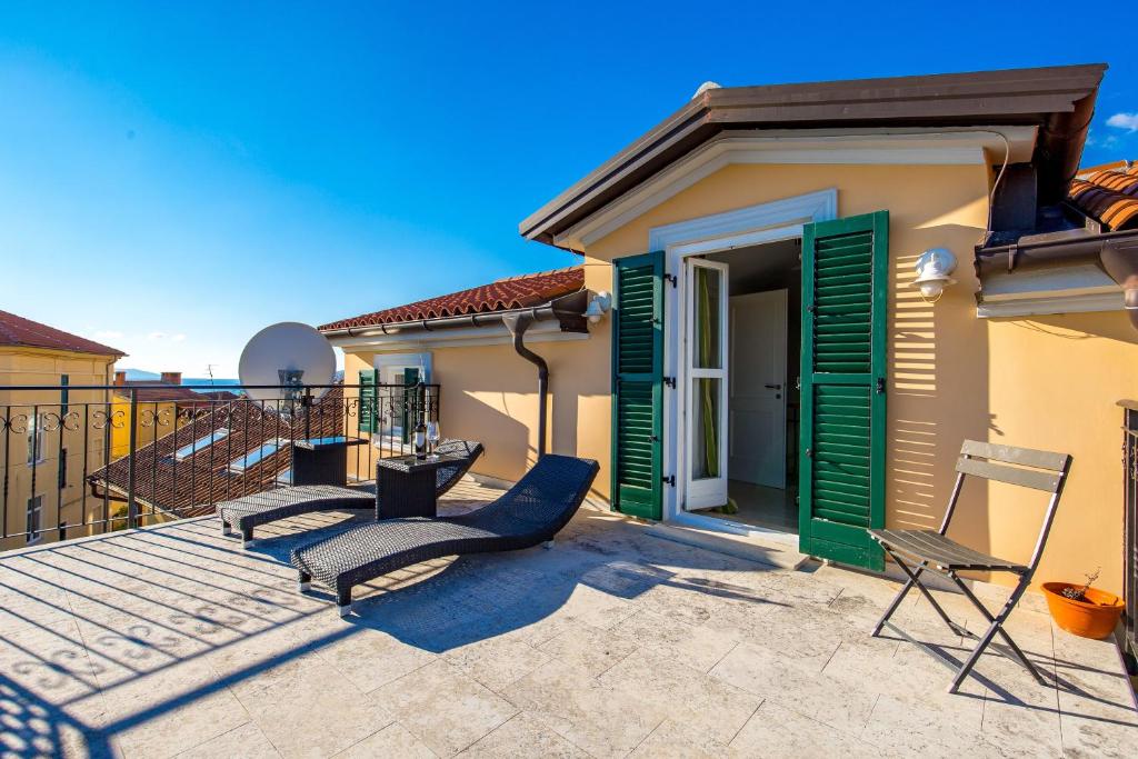 a deck with chairs and a house with green shutters at Charmante Villa Vilma In Opatija in Opatija