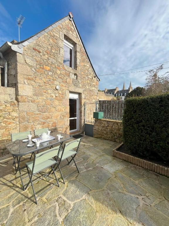 un patio avec une table et des chaises devant un bâtiment dans l'établissement Maison bretonne 2 personnes centre ville St Pol de Léon, à Saint-Pol-de-Léon