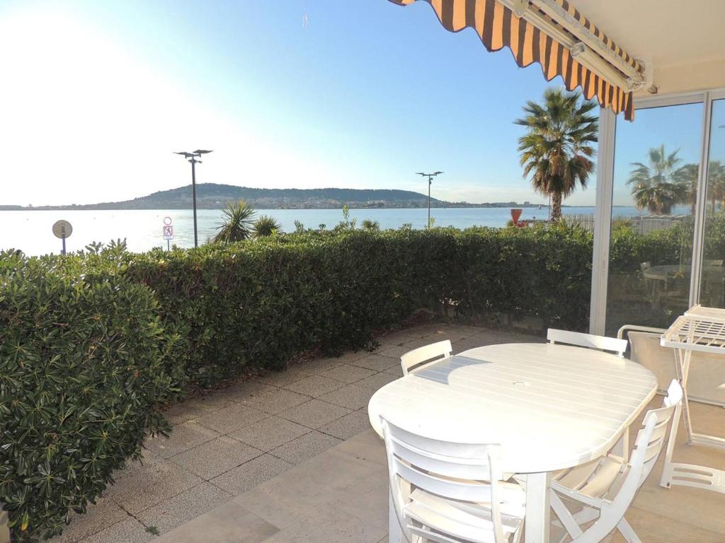 - une table et des chaises blanches sur une terrasse donnant sur l'eau dans l'établissement F2 3* avec Parking et Terrasse, Face à l'Étang de Thau, Proche Thermal, Tout Équipé - FR-1-571-10, à Balaruc-les-Bains