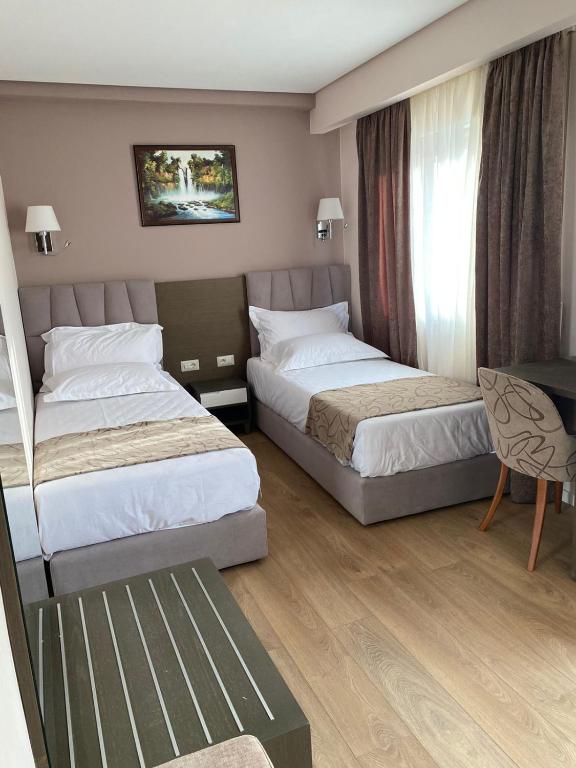 a hotel room with two beds and a chair at Doanesia Premium Hotel & Spa in Tirana
