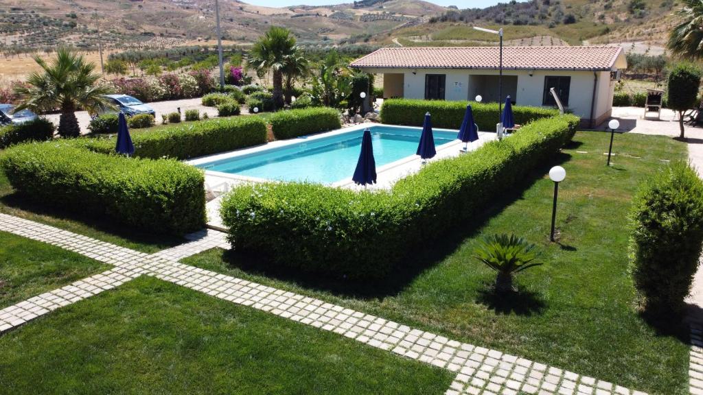 a swimming pool in a yard with bushes and umbrellas at Wohnung 4 Studio in Cattolica Eraclea