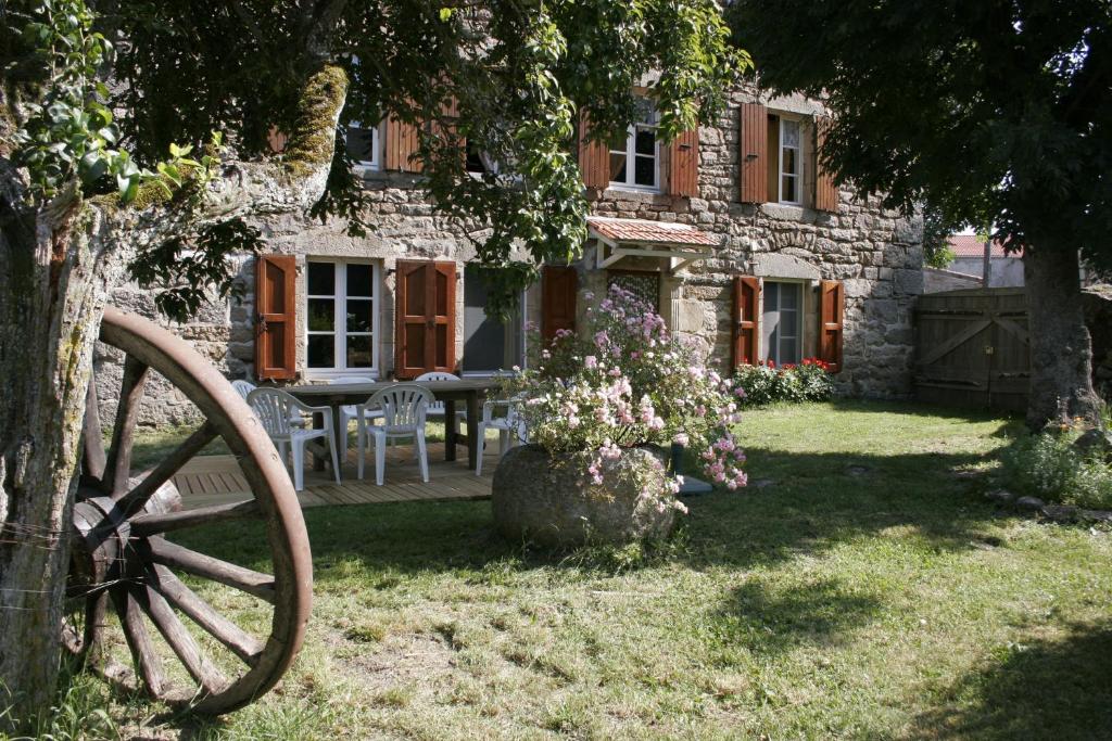 a stone house with a table and chairs in the yard at La maison d'Anastasie in Saint-Étienne-du-Vigan