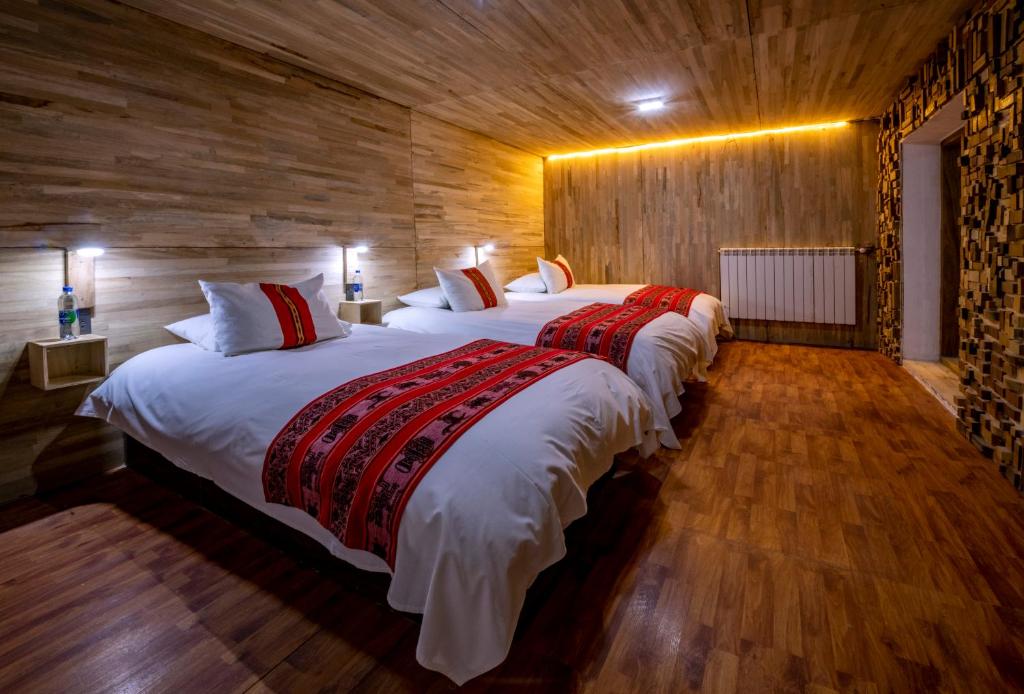 Habitación con 2 camas grandes y paredes de madera. en Flamencos Altiplano Eco Hotel, en Ramaditas