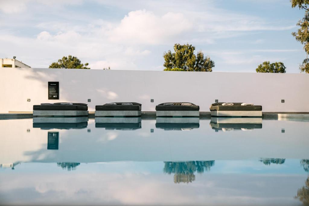 a white wall with four chairs in a pool of water at Kalisti Hotel & Suites in Fira