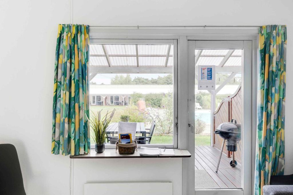 NeksøにあるCozy Holiday Apartment Close To The Beachのパティオに面したガラスのスライドドアが付いた客室です。