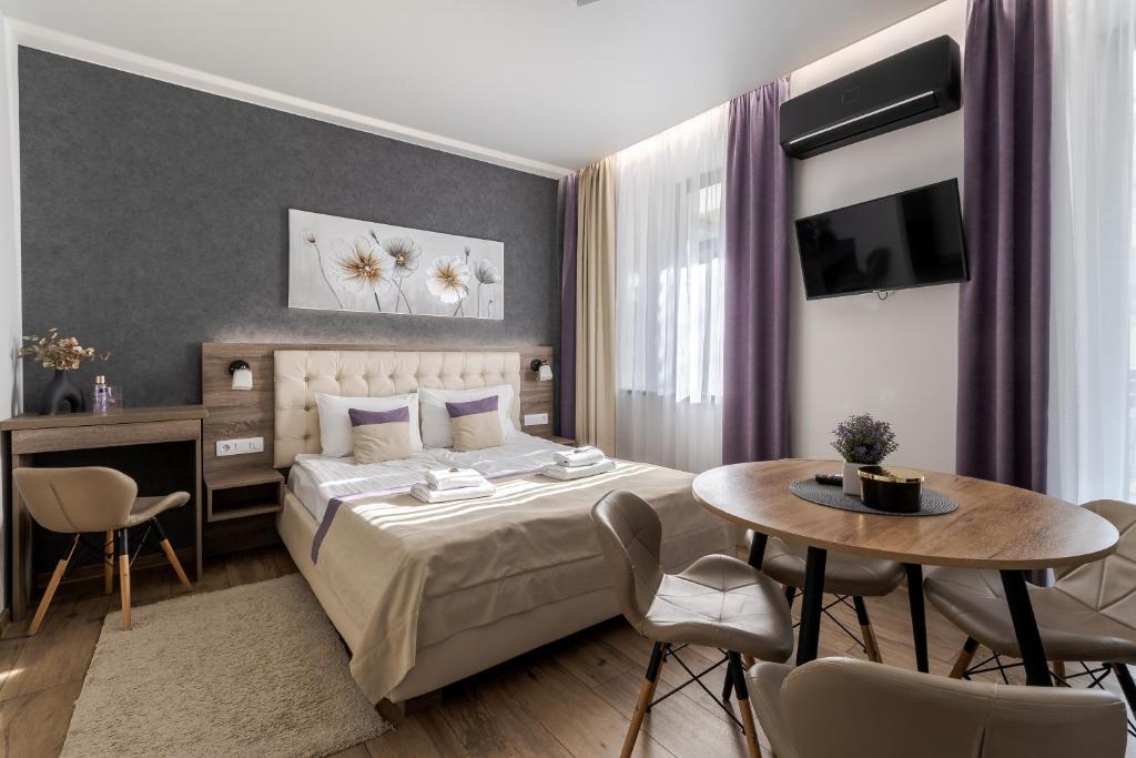 une chambre avec un lit, une table et des chaises dans l'établissement DeMar Apart Violet, à Lviv