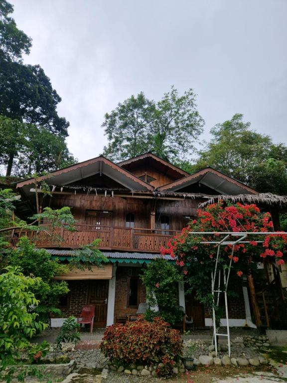 a house with red flowers in front of it at Sultan Guesthouse in Bukit Lawang