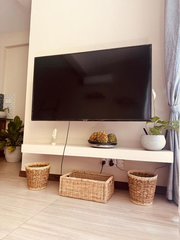 a flat screen tv on a wall with baskets at Unit One by Hideout Lounge in Kandy