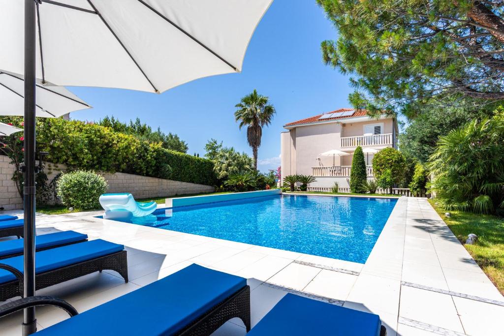 una piscina con sedie blu e un ombrellone accanto a una casa di Helle Studio Ferienwohnung Mit Sonnenbalkon a Splitska