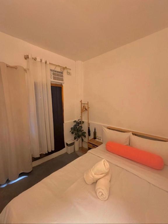 a bedroom with a large white bed with an orange pillow at Akap Homestay - Daku in General Luna