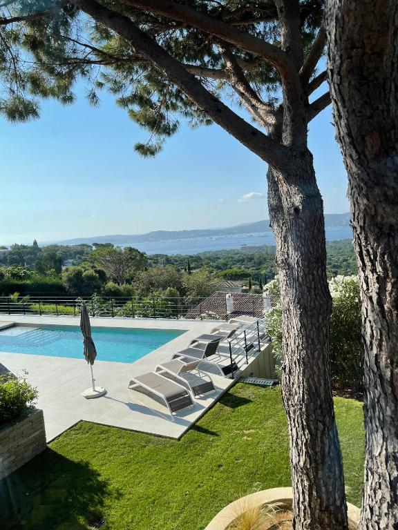 un groupe de chaises longues assises à côté d'une piscine dans l'établissement Villa Les 3 Pins - Spacious Escape with Private Pool and Panoramic Views of the St-Tropez Gulf, à Port Grimaud