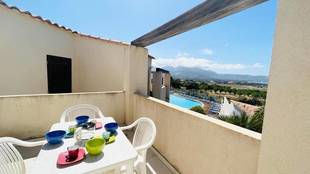 une table blanche et des chaises sur un balcon avec vue dans l'établissement Appartement 2 pièces 4 couchages LUMIO, à Lumio