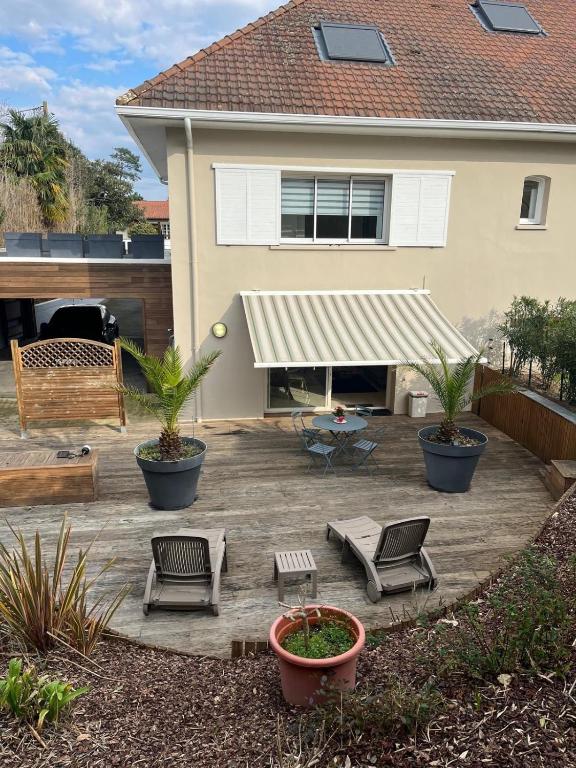 une terrasse avec des chaises et un auvent en face d'une maison dans l'établissement Anglet Chiberta - Proche plage et golf, à Anglet