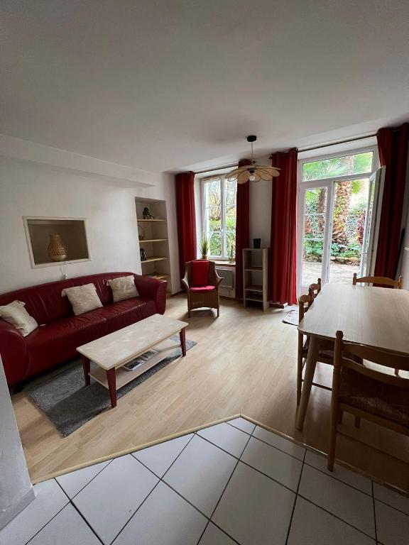 un salon avec un canapé rouge et une table dans l'établissement Les Platanes - Cézanne Rez de Jardin, à Lamalou-les-Bains