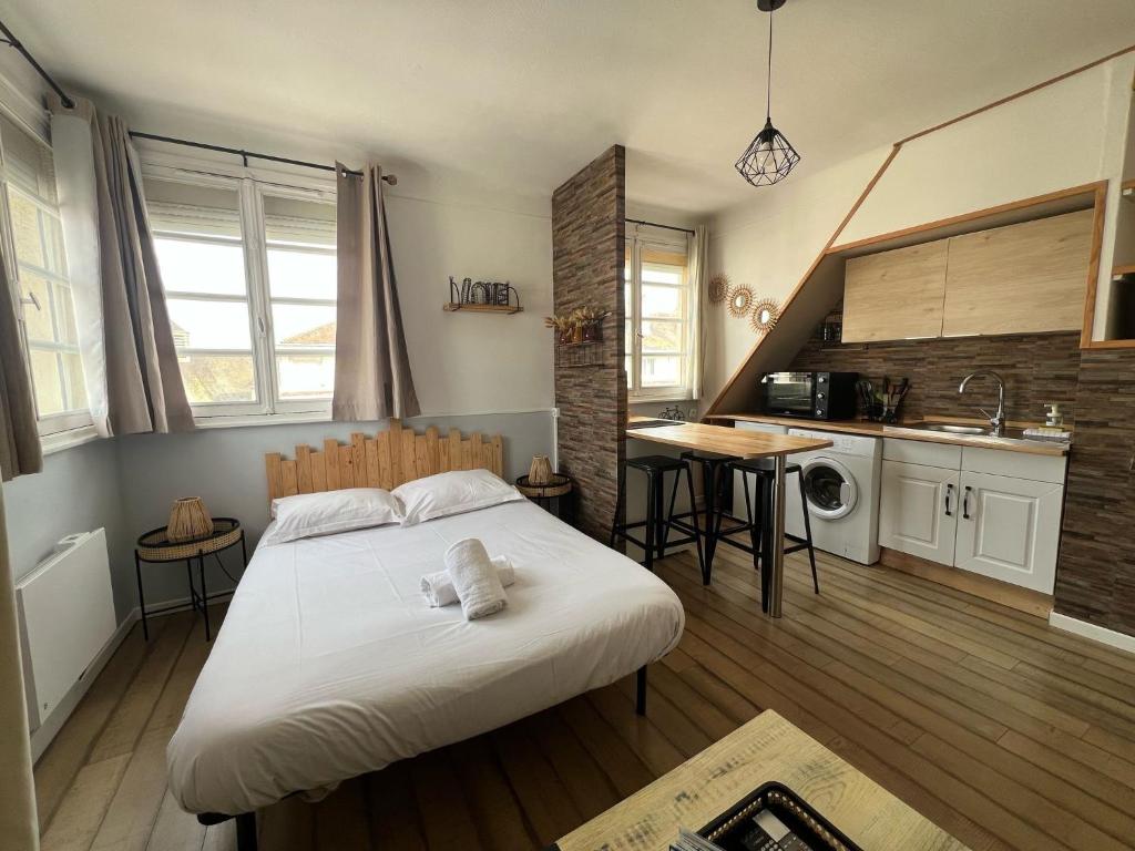 une chambre avec un grand lit et une cuisine dans l'établissement Le Marin, à Calais