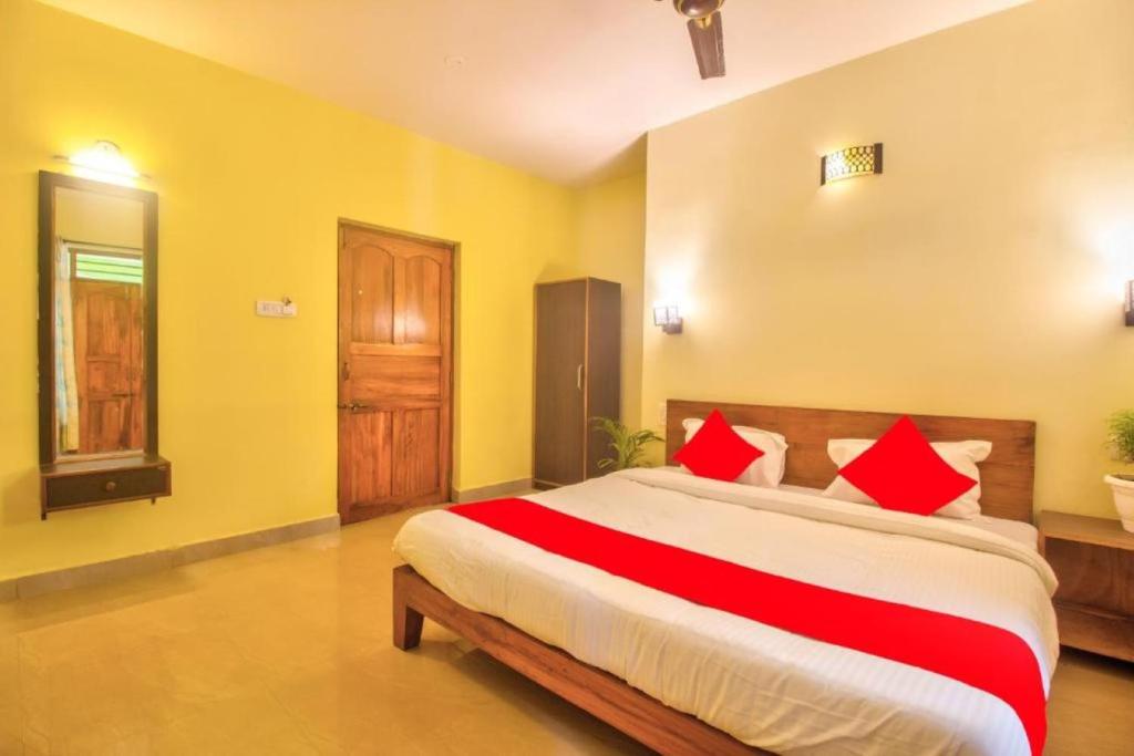 a bedroom with a large bed with red pillows at Roseal Beach Front in Baga