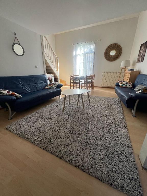 un salon avec un canapé bleu et une table dans l'établissement Les Platanes - Dali, à Lamalou-les-Bains