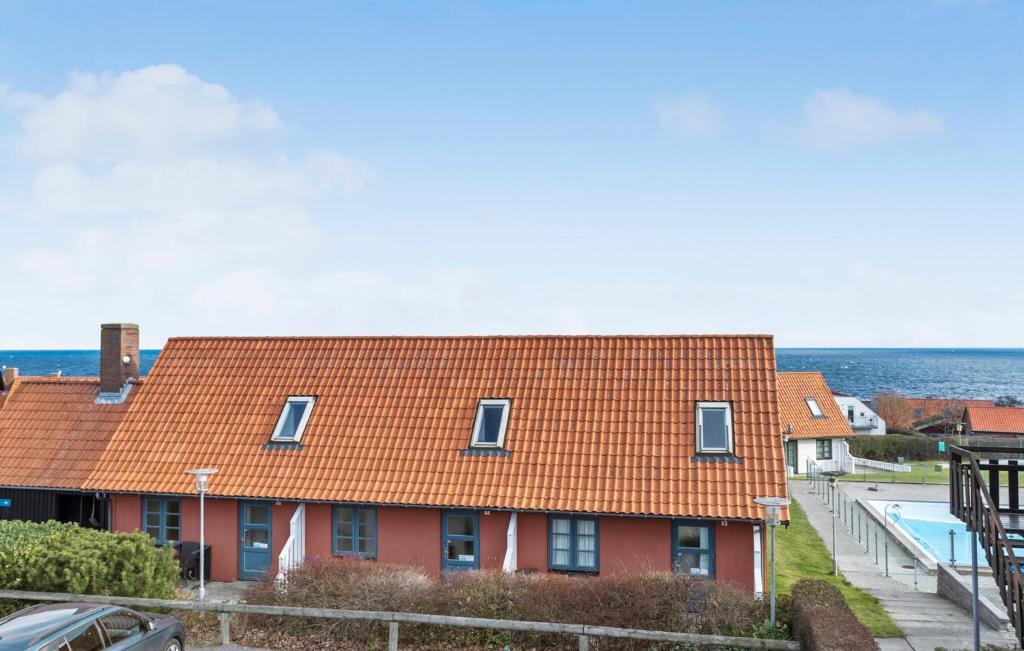 a red house with an orange roof next to a swimming pool at Cozy Apartment In Gudhjem With Sauna in Gudhjem