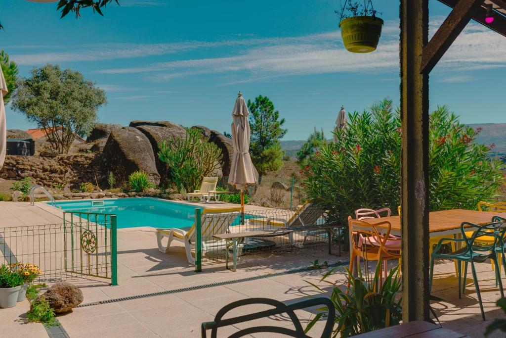 a patio with a pool and a table and a umbrella at Quinta da Estrela in Ponte Nova