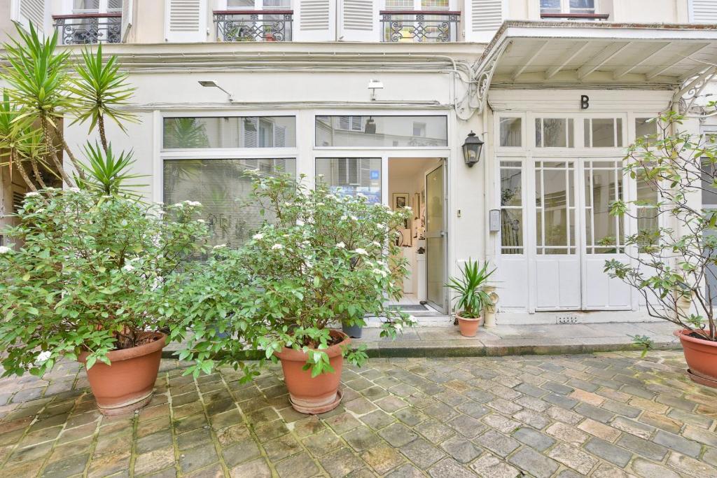 une maison avec des plantes en pot devant une porte dans l'établissement Atelier d’artiste, à Paris