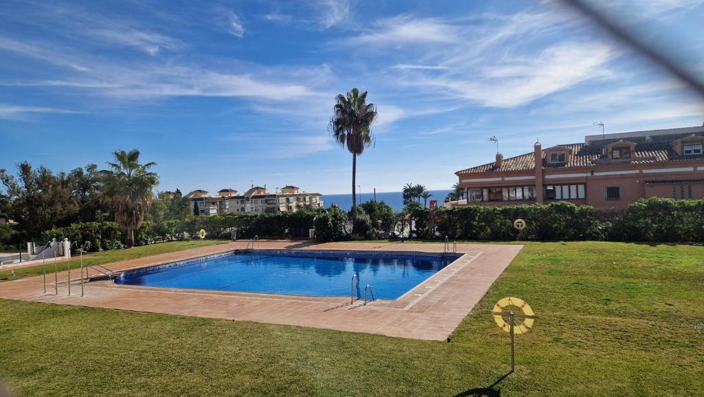 a swimming pool in a yard with a palm tree at Beautiful apartment in Calahonda beach in Sitio de Calahonda