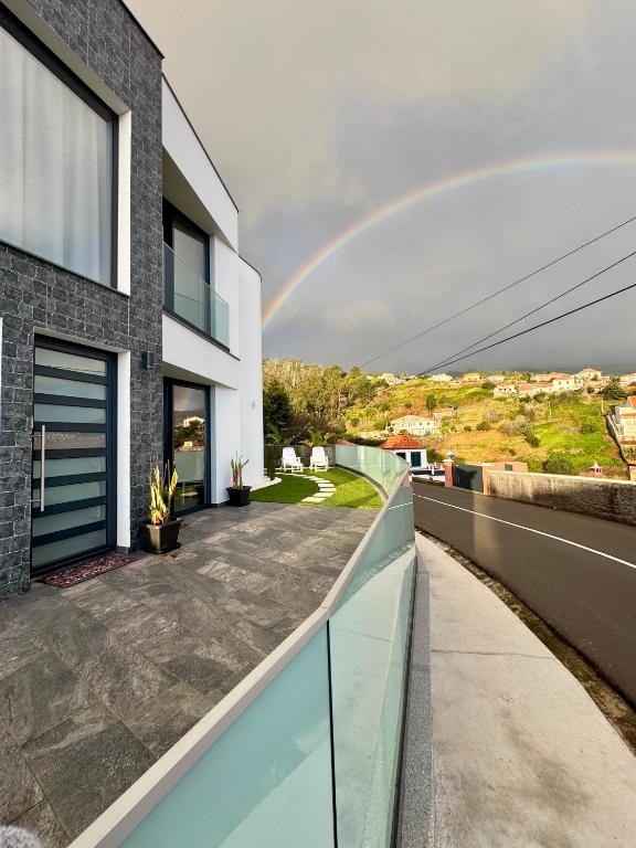a rainbow in the sky over a house at Calheta Nest in Calheta
